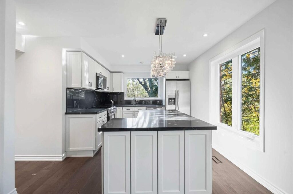 Bright kitchen renovation in the GTA with large window, white cabinets, black countertop, and island