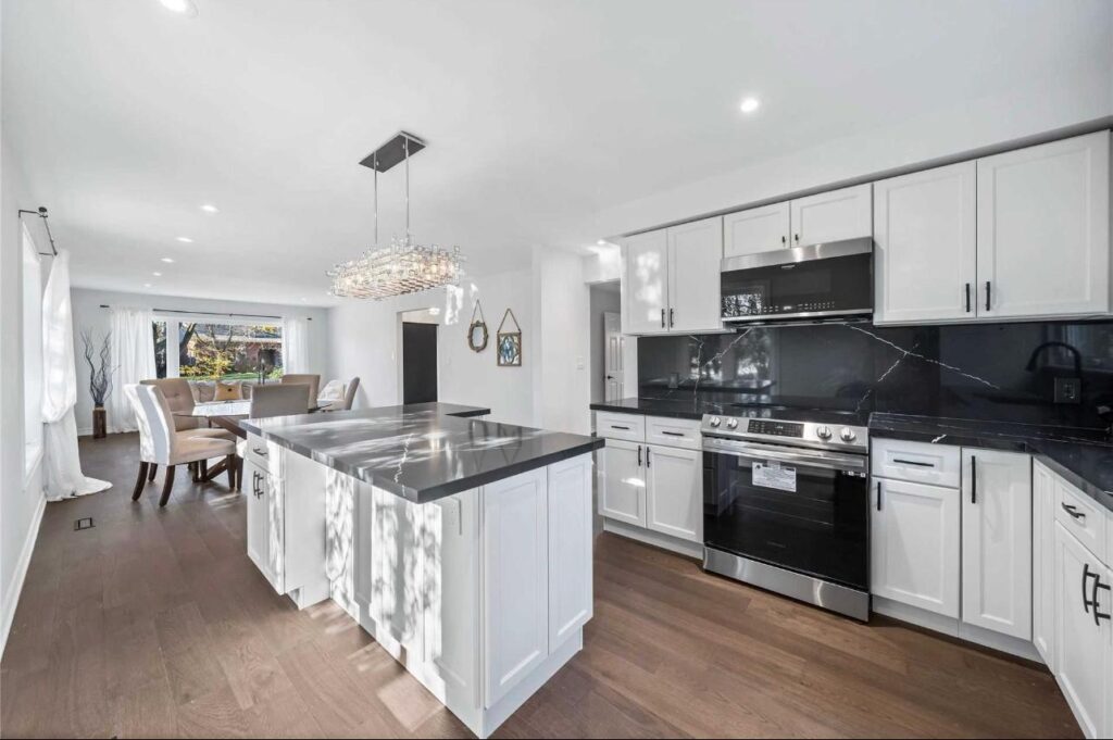 Custom kitchen renovation in Toronto with white cabinets, black backsplash, and open dining area