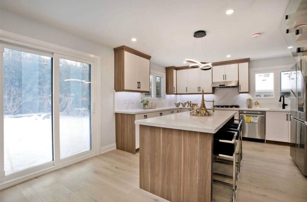Modern kitchen renovation in Toronto with white and wood cabinets, island, and bright natural light