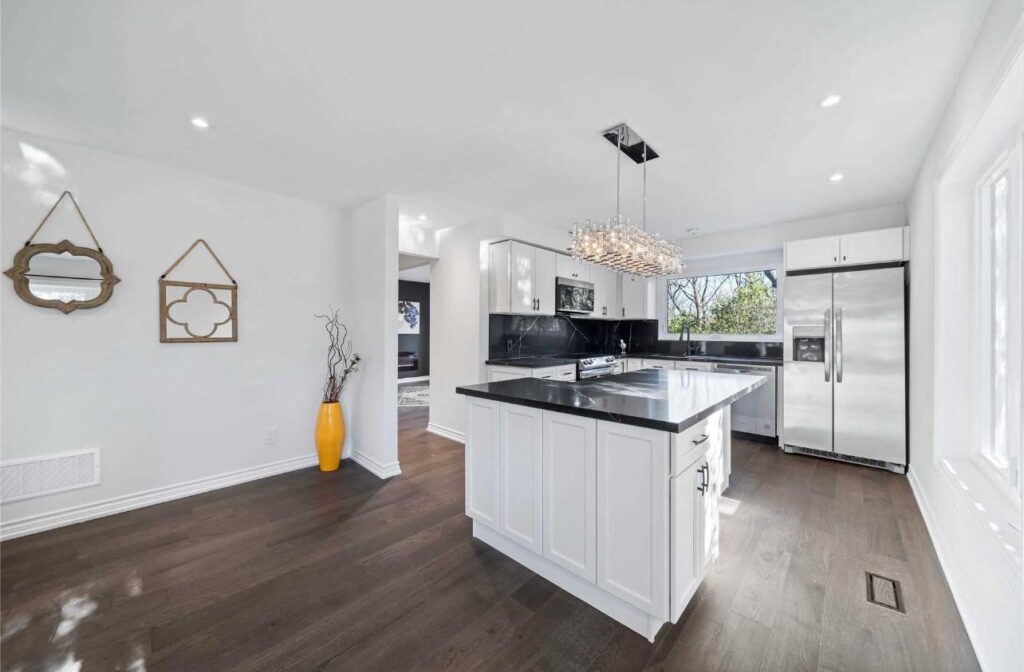 White kitchen renovation in Richmond Hill with black countertop, island, and stainless steel appliances
